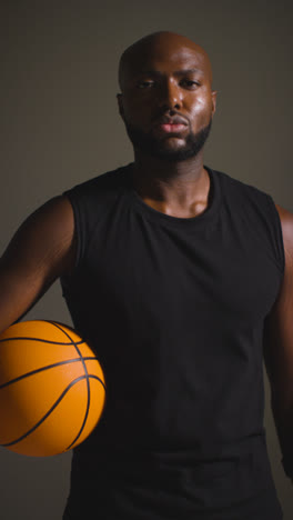 Vertical-Video-Studio-Vertical-Video-Portrait-Shot-Of-Male-Basketball-Player-Holding-Ball-Towards-Camera